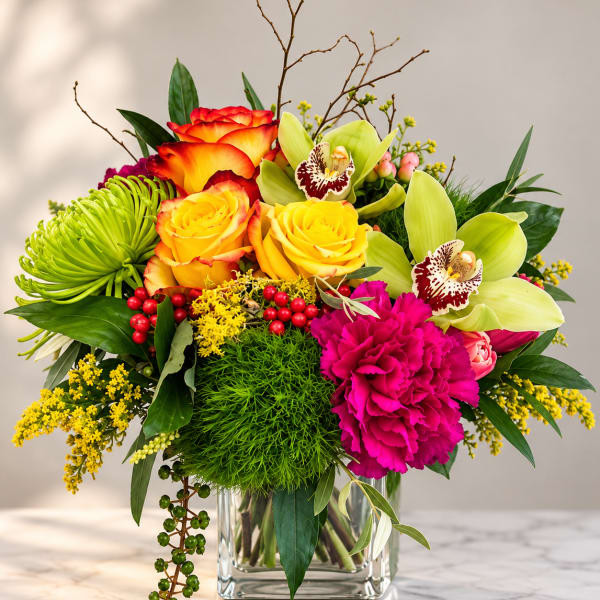 Colorful bouquet in a clear glass vase with roses, orchids, and carnations