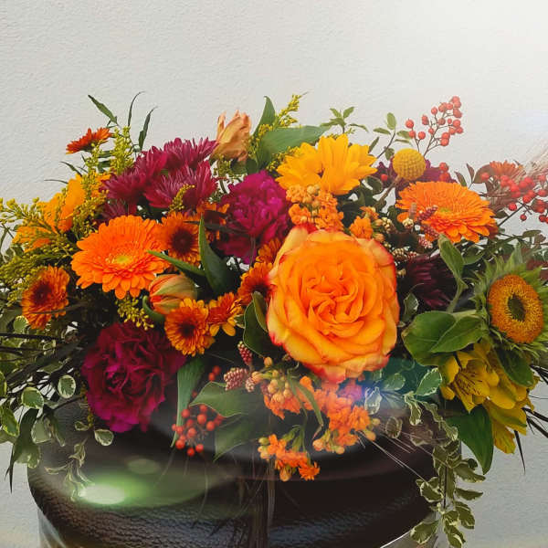 Bright mixed bouquet with orange and magenta flowers in a dark vase