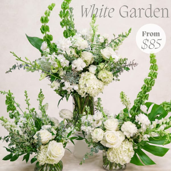 White floral arrangement in a glass vase with tall green spikes