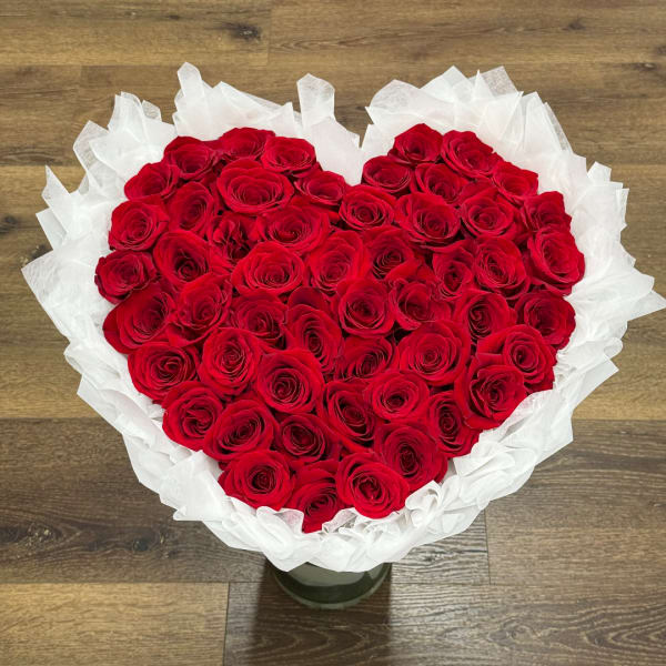 Heart-shaped bouquet of red roses wrapped in white paper