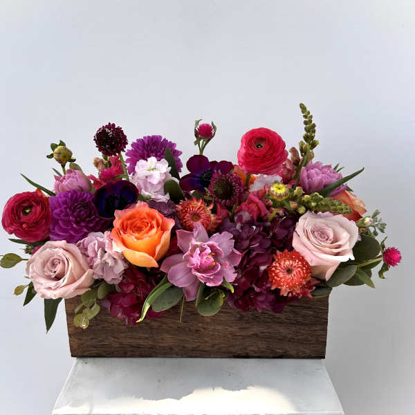 Mixed bouquet in a wooden box with pink, purple, orange, and white flowers