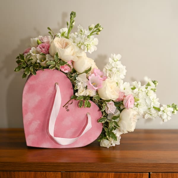 Pink heart-shaped box filled with white and blush flowers