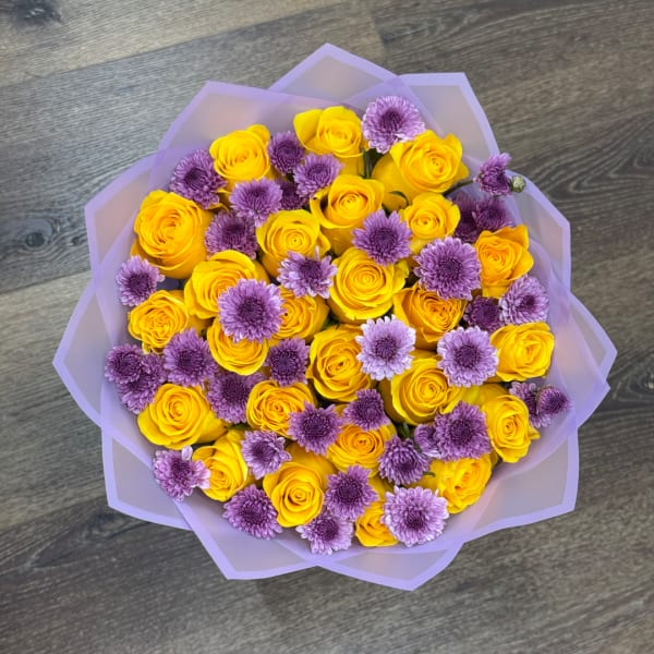 Yellow roses and purple chrysanthemums wrapped in lavender paper