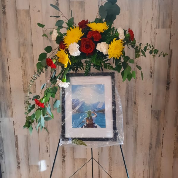 Floral standing spray with red, yellow, and white flowers on an easel