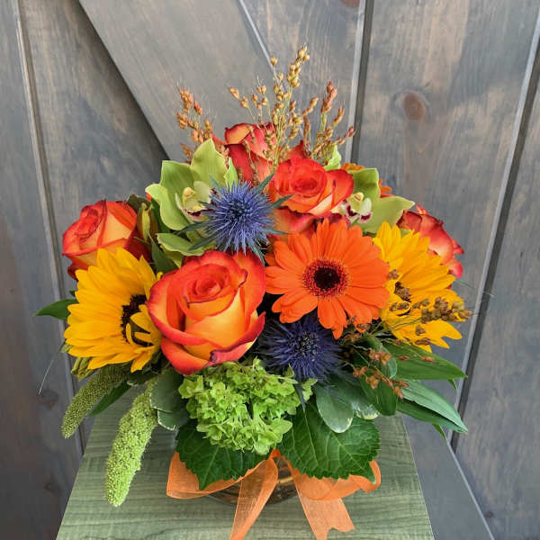 Bouquet of orange roses, sunflowers, and an orange gerbera daisy in a vase