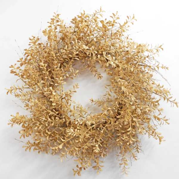 Dried golden wreath with small clustered leaves on a white background