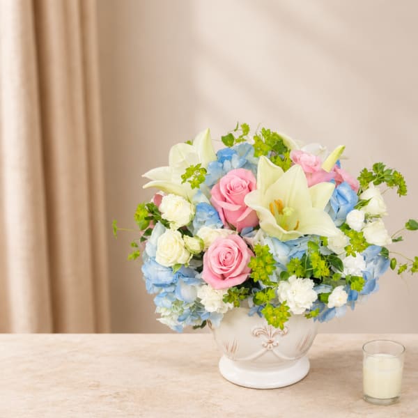 Pastel bouquet of roses, lilies, and hydrangeas in a white vase