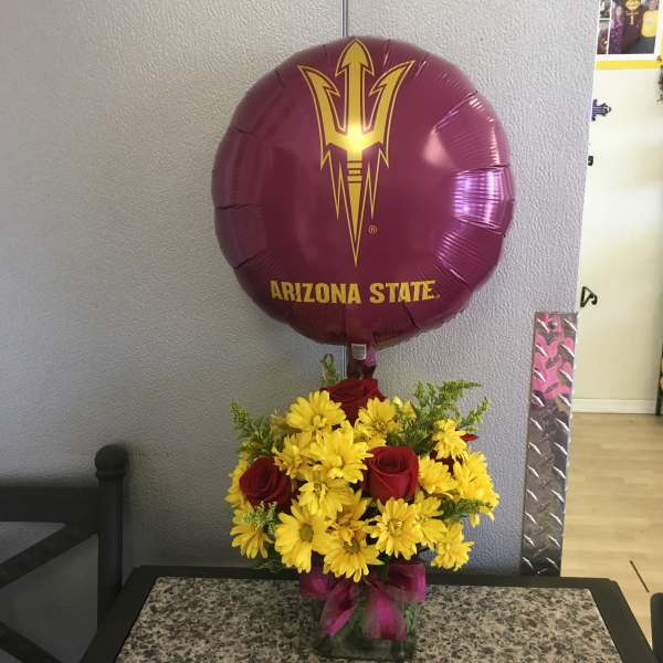 Yellow daisies and red roses in a vase with an Arizona State balloon