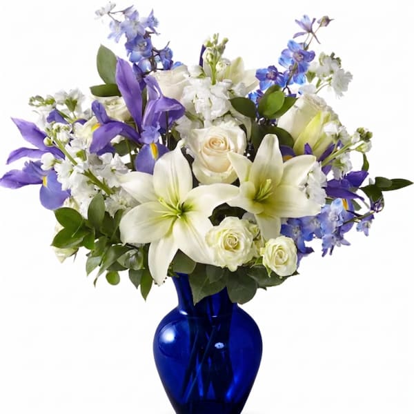 White lilies, roses, and purple flowers in a blue glass vase