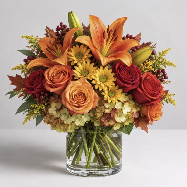 Orange lilies and roses in a glass vase with yellow flowers