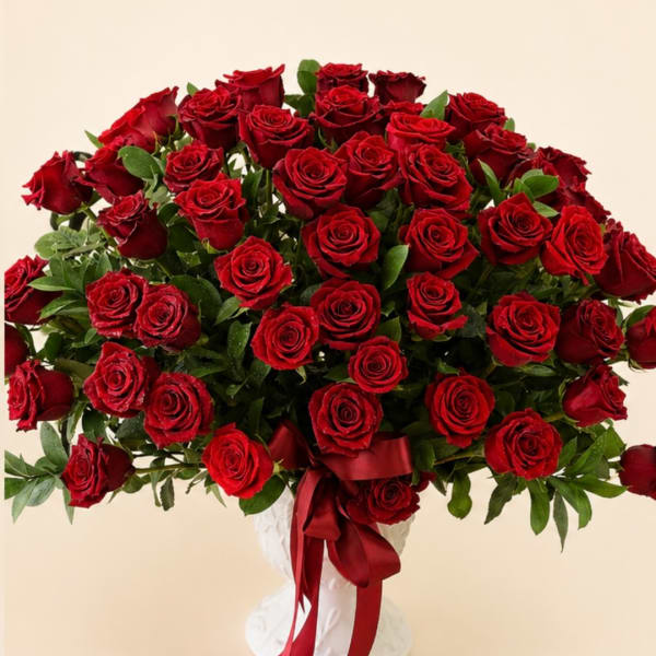 Large bouquet of red roses in a white vase with a red ribbon