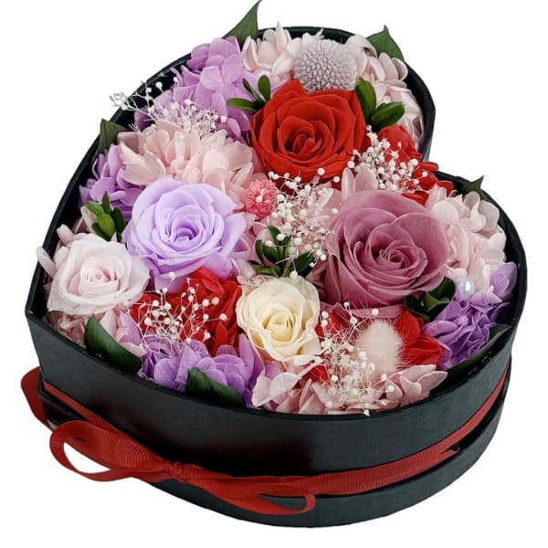 Heart-shaped box of pastel and red roses with a ribbon bow
