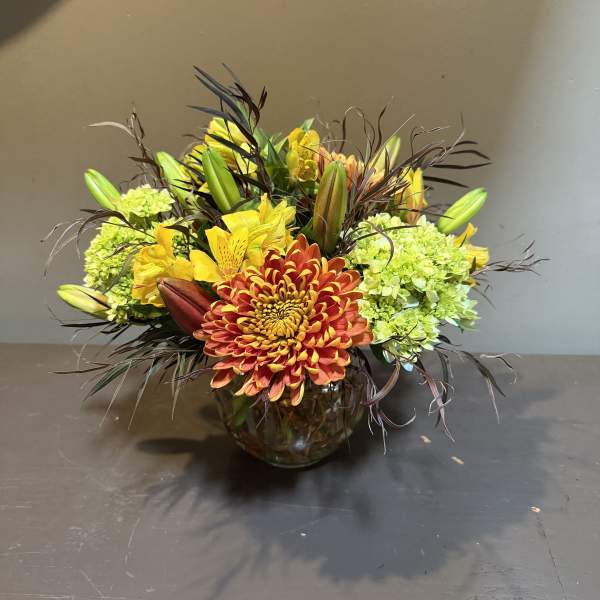 Orange chrysanthemum bouquet with green hydrangeas in a glass vase