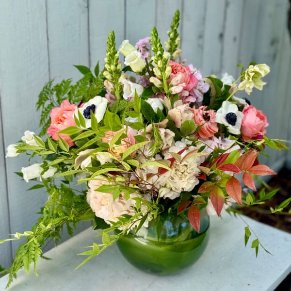 Mixed bouquet of pink, white, and green flowers in a green glass vase