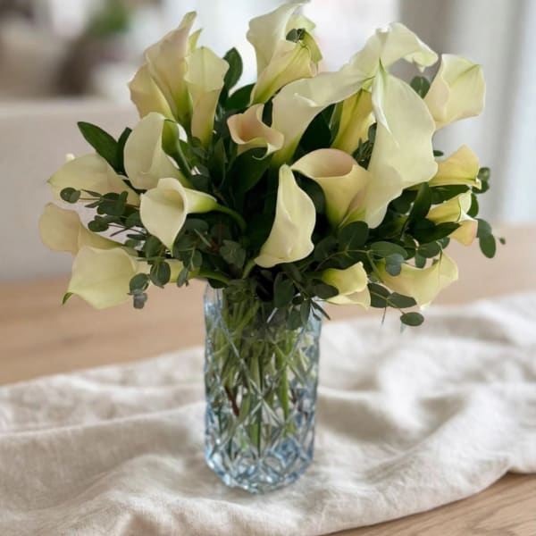 Bouquet of pale calla lilies in a clear glass vase