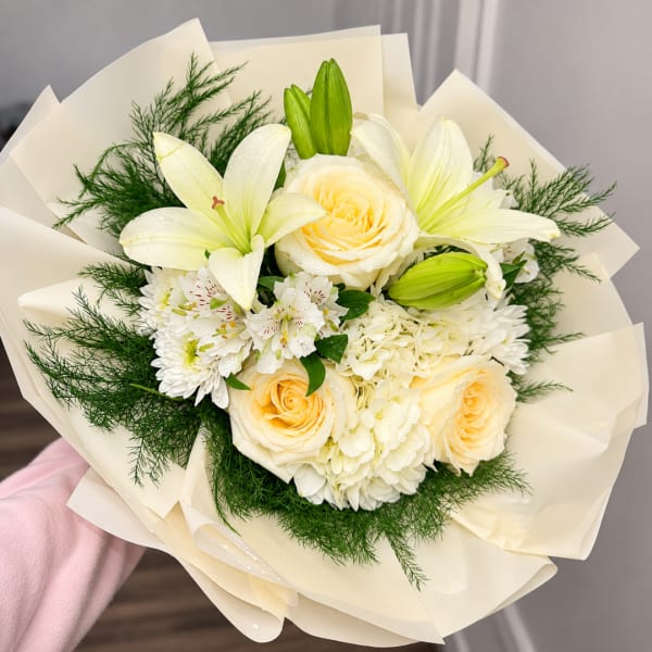 Cream roses and white lilies in a wrapped bouquet