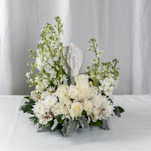 White floral arrangement with roses and a small angel figurine