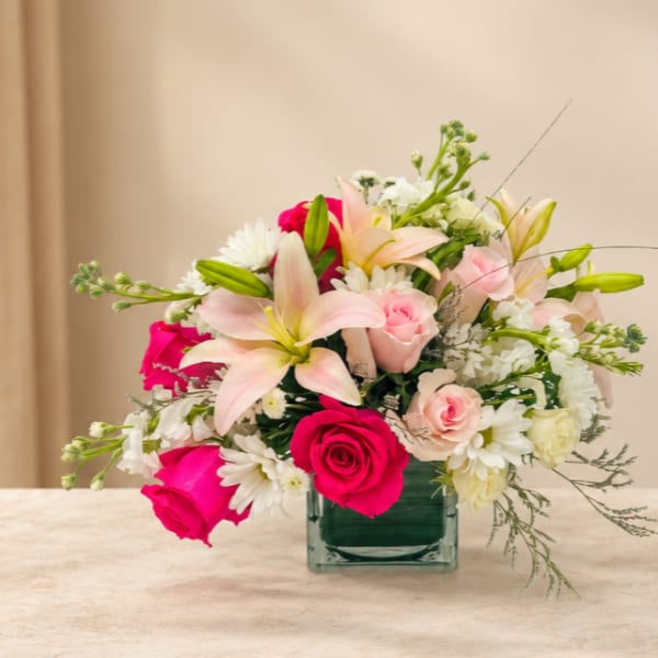 Pink and white mixed flower arrangement in a square glass vase