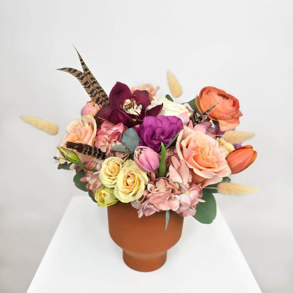 Mixed bouquet in a terracotta vase with roses and orchids