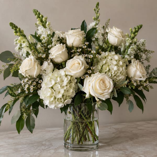 White roses and hydrangeas in a clear glass vase