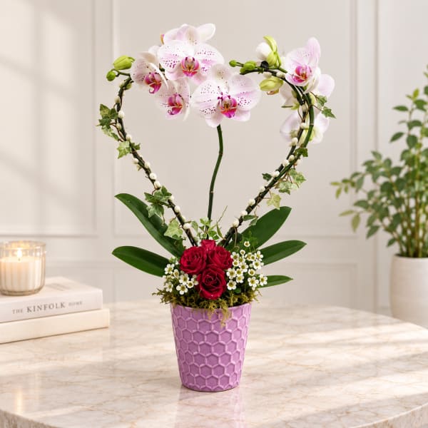 Heart-shaped orchid and rose arrangement in a purple vase