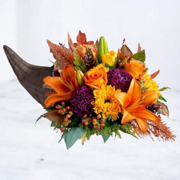 Orange and yellow floral arrangement with lilies and roses in a horn-shaped container