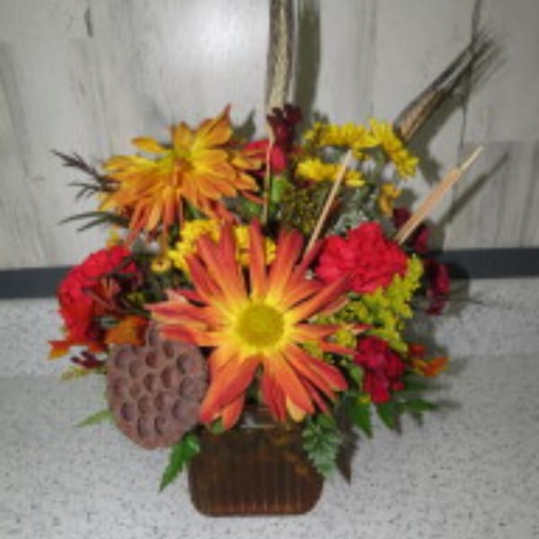 Orange and red mixed flower arrangement in a brown basket