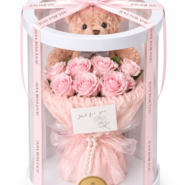 Pink rose bouquet in a clear gift box with a teddy bear and ribbon