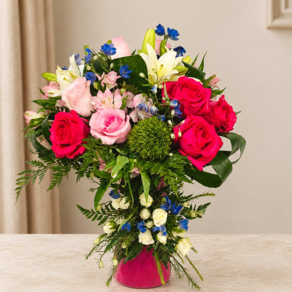 Mixed bouquet of pink and red roses with white lilies in a vase