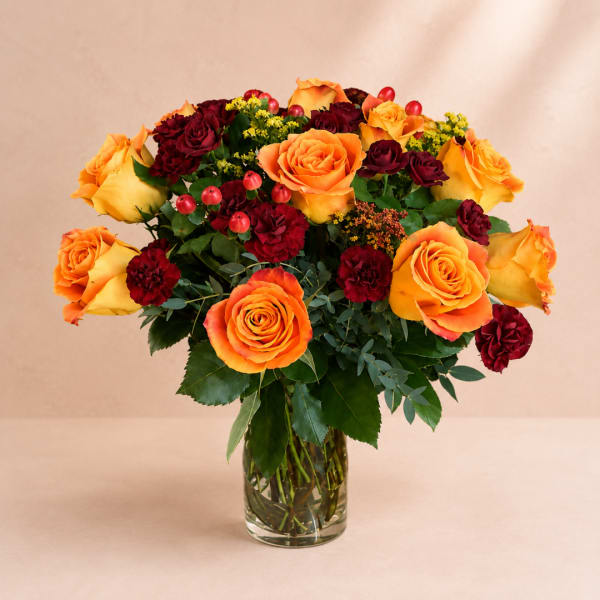 Orange and burgundy roses in a clear glass vase