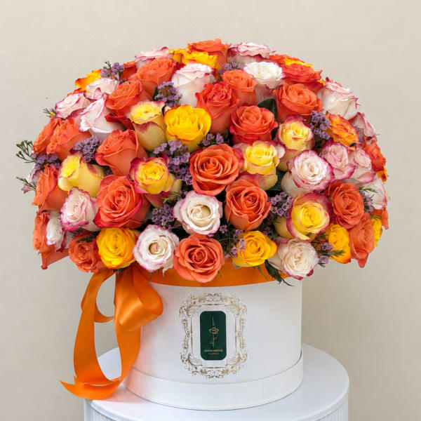 Bouquet of orange, yellow, pink, and white roses in a white hat box with ribbon