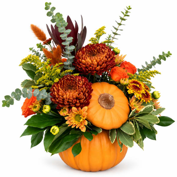 Autumn floral arrangement in a pumpkin container with orange and burgundy blooms