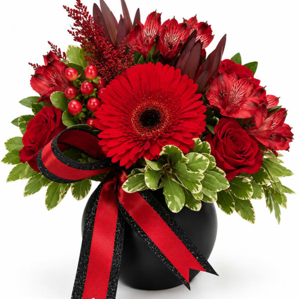 Red flowers arranged in a black vase with a red-and-black ribbon