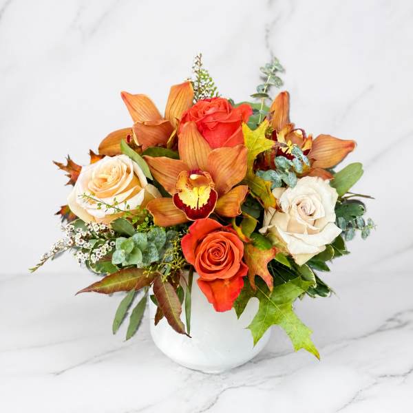 Orange and white roses with orchids in a white vase