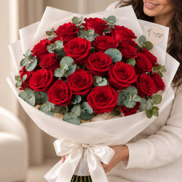 Bouquet of red roses wrapped in white paper with a satin ribbon