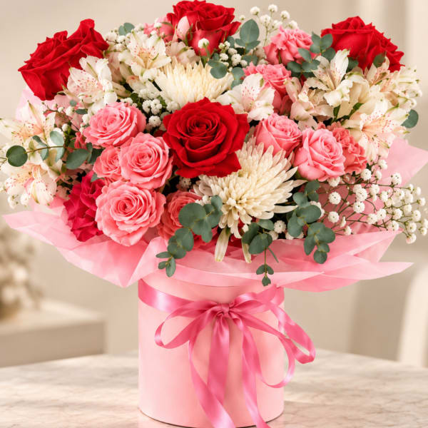 Pink and red rose bouquet in a pink hatbox with ribbon