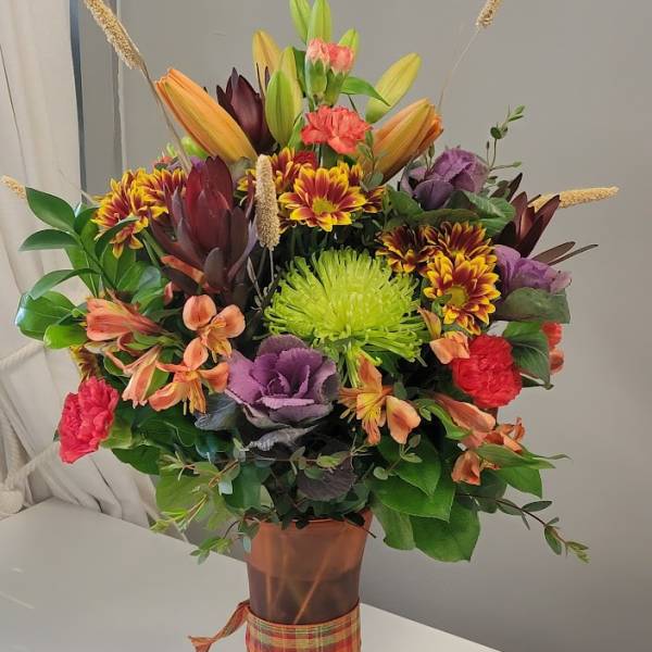 Mixed bouquet in a copper vase with orange, purple, and green flowers