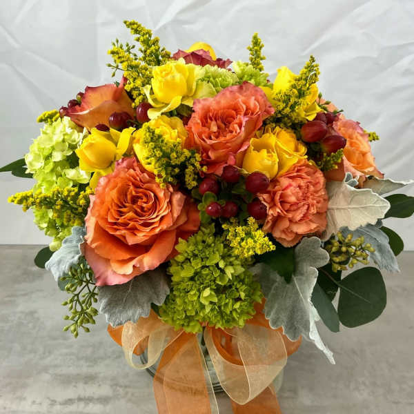 Orange and yellow rose bouquet in a glass vase with ribbon