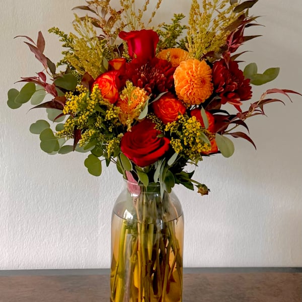 Red and orange flower bouquet in a glass vase