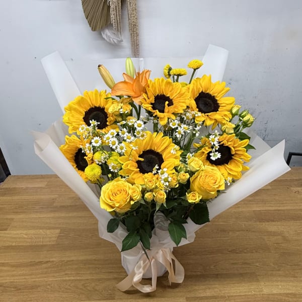 Bouquet of yellow sunflowers and roses wrapped in white paper