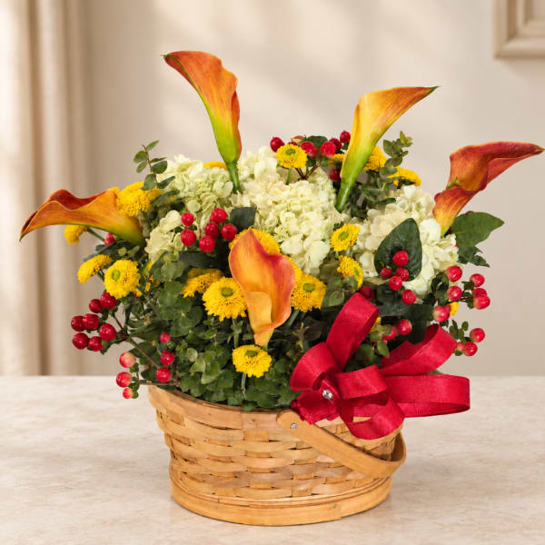 Basket arrangement with orange calla lilies, white hydrangeas, and yellow daisies