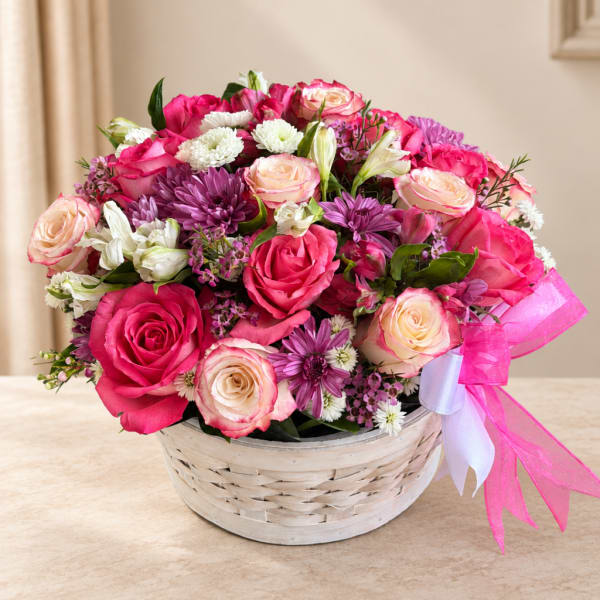 Pink and cream roses with purple flowers in a white basket