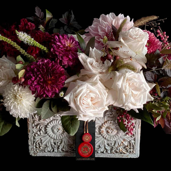 Mixed bouquet of white roses and magenta blooms in an ornate rectangular container