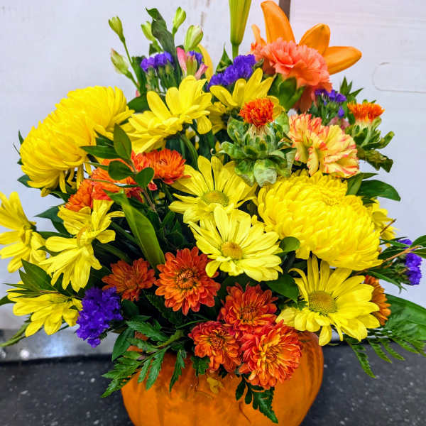 Mixed yellow and orange flowers arranged in a pumpkin container