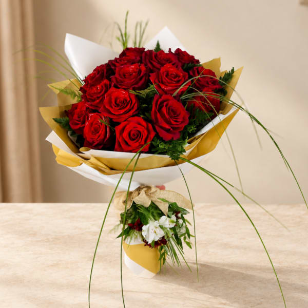Bouquet of red roses wrapped in white and gold paper