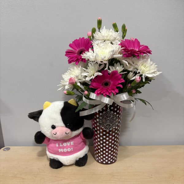 Pink and white daisy bouquet in a polka-dot vase with a plush cow