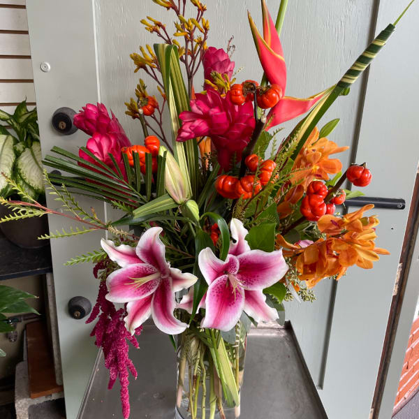 Tropical bouquet with pink lilies and orange flowers in a glass vase