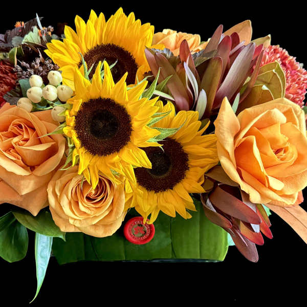 Orange roses and sunflowers arranged in a low rectangular container