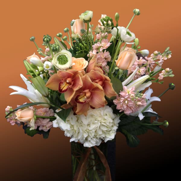 Mixed bouquet with orchids, roses, lilies, and hydrangea in a glass vase