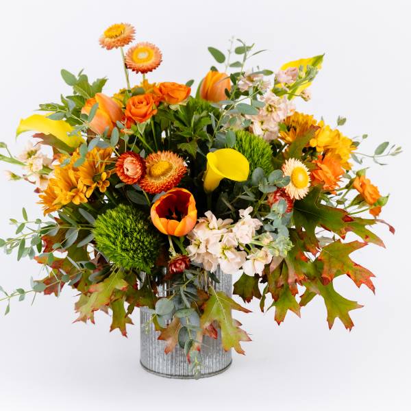 Autumn bouquet of orange and yellow flowers in a metal container
